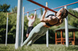© qunica.com - Two individuals perform calisthenics exercises in an urban park, utilizing outdoor bars on a sunny day, promoting fitness and a healthy lifestyle.