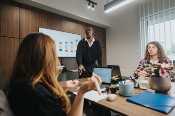 Wall Mural - A professional group of colleagues collaboratively discussing business strategies and analytics in their office. Focus on team leadership and engagement.