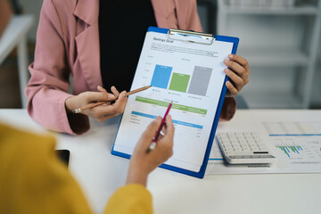 Fototapete - Business Meeting with Financial Analysis on Clipboard, Two Professionals Discussing Savings Goals, Analyzing Data with Calculator, Office Environment, Teamwork, Financial Planning, Business Strategy