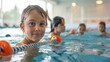 © MarkFinal - Happy kids learning swimming in an indoor summer pool with a safety rope