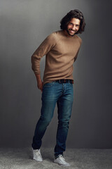 Poster - Smile, man and portrait with fashion in studio for elegant, style and comfortable winter jeans clothes. Cool, male person and trendy jersey, designer wardrobe or hands in pocket on grey background