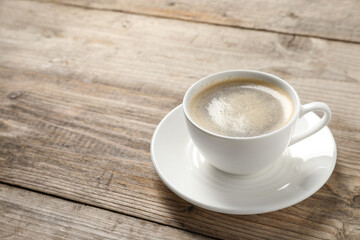 Wall Mural - Tasty coffee in cup on wooden table, closeup. Space for text