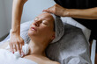 © MarijaBazarova - Middle aged female receiving facial massage in beauty salon. Anti aged massage and skincare concept with a beautiful woman. Hands of cosmetology specialist making facial lifting massage in SPA salon
