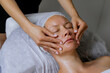 © MarijaBazarova - Middle aged female receiving facial massage in beauty salon. Anti aged massage and skincare concept with a beautiful woman. Hands of cosmetology specialist making facial lifting massage in SPA salon
