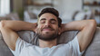 © Alex Alex - Portrait of a smiling young man resting and relaxing on the couch at home with his eyes closed and his hands behind his head