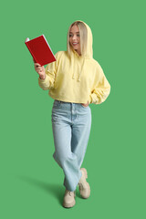 Wall Mural - Beautiful young happy woman with book on green background
