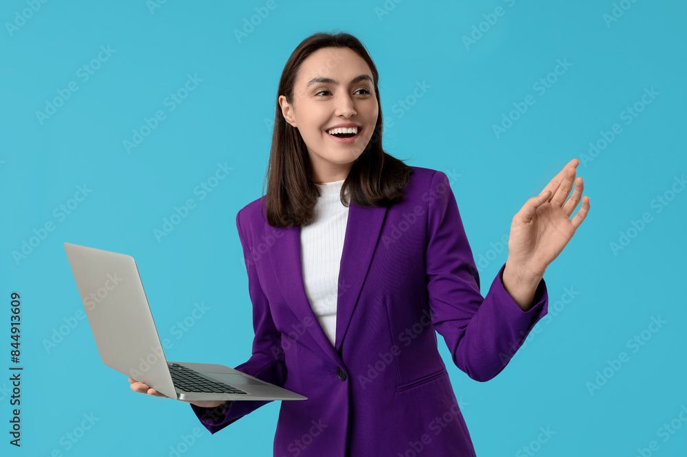 Young businesswoman with laptop on blue background
