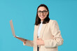 © Pixel-Shot - Young businesswoman with laptop on blue background