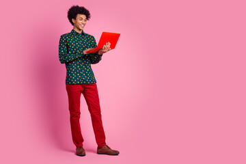 Poster - Full size photo of clever positive guy with wavy hair dressed print shirt look at laptop chatting isolated on pink color background