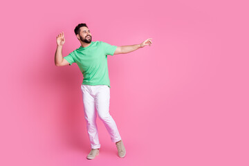 Canvas Print - Full size photo of carefree handsome guy dressed green t-shirt white pants look empty space dancing isolated on pink color background