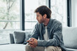 © Daniel - Thoughtful serious man sitting on sofa alone at home, lost in thoughts, thinking about problem solving, feeling lonely, making important decision, having psychological problem, side view.