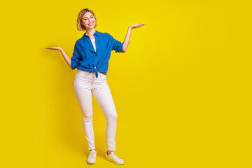 Wall Mural - Full body portrait of pretty young lady hold empty space scales wear shirt isolated on yellow color background