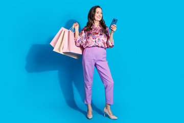 Poster - Photo of successful gorgeous retired woman wear trendy clothes hold packages isolated on blue color background