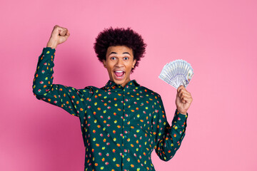 Canvas Print - Portrait of ecstatic guy with wavy hairstyle dressed print shirt holding money win gambling raising fist isolated on pink color background