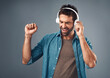 © peopleimages.com - Dance, man and headphone for music in studio, audio media and podcast or ebook on gray background. Technology, streaming and online subscription for song, male person and smile for listening