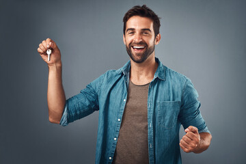 Celebrate, portrait and happy man with key in studio for real estate, property or new home owner on gray background. Rent, tenant and excited person for purchase, achievement or investment on mockup