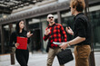 © qunica.com - Three professionals engage in a conversation outside an office building, exchanging ideas with documents in hand.