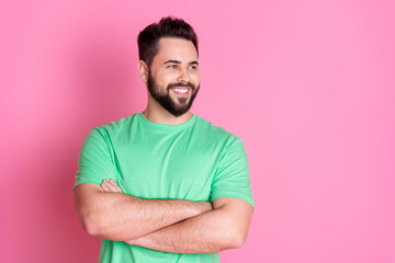 Sticker - Photo of positive handsome guy with stylish beard dressed green t-shirt look empty space arms crossed isolated on pink color background