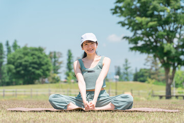 Canvas Print - 公園でヨガマットを使ってヨガ・ストレッチ・運動をする女性
