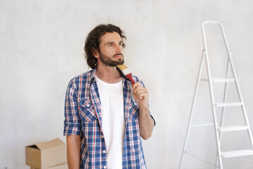 Wall Mural - Thoughtful Man Holding Paintbrush Planning Home Renovation