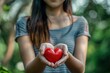 © MadMouse - Young woman holding a red heart in her hands