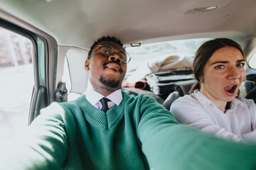 Two business colleagues sharing a fun and casual moment in the backseat of a car, portraying a relaxed corporate atmosphere.