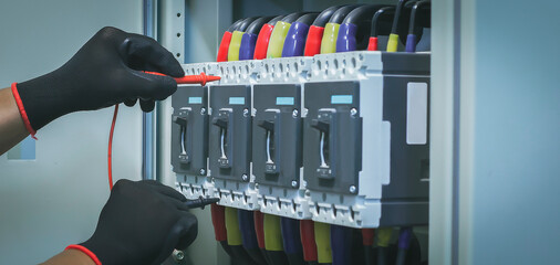 Wall Mural - Electrical engineer tests the operation of the electric control cabinet on a regular basis for maintenance.