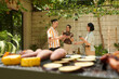 © DragonImages - Smiling young people having wine and eating grilled hotdogs at outdoor party
