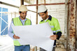 © offsuperphoto - workers or architects holding and reading plan blueprint paper at construction site