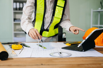 Wall Mural - businessman hand working and laptop with on on architectural project at construction site