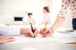© Halfpoint - Close up on hands writing on paper, people working on a new project together in a startup company office. Working in co-working space.