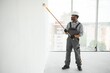 © Serhii - African man in a helmet paints a white piece of wall with paint