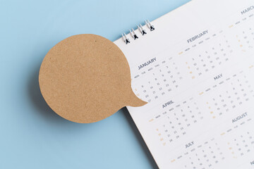 top view of real blank grunge brown paper cut on blurred yearly calendar on blue background for impo