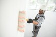 © Serhii - African man paints a white wall with a roller. Repair of the interior