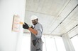 © Serhii - African man paints a white wall with a roller. Repair of the interior