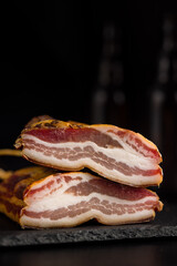 Poster - Closeup of Sliced Smoked Bacon on  Black Slate Cutting Board