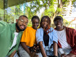 © DimaBerlin - Four smiling African American college students take selfie outside university library take study break. Pleased black diversity friends looking at camera have fun together.