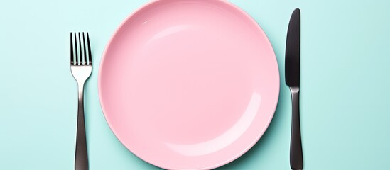 Aufkleber - Top view of a clean blue ceramic plate accompanied by a stainless knife and fork isolated on a pink background The cutlery is neatly organized ready for a delicious meal Copy space is available for y