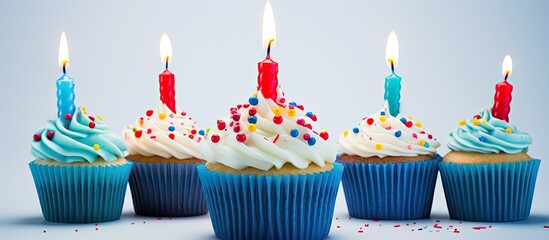 Poster - A festive cupcake with multi colored candles covered in blue glaze and bright decorations set against a white background providing ample copy space for an image