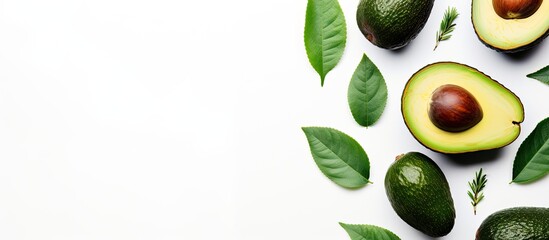 Wall Mural - Top view of a white background with a fresh ripe avocado accompanied by green leaves Ideal for flat lay photography with plenty of room for text or other images. Creative banner. Copyspace image