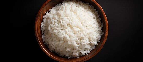 Poster - A high resolution top view image showing white rice spread across a black background providing ample space for text It conveys a concept of healthy food