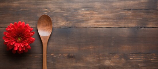 A rustic wooden spoon and fork featuring a vibrant red flower are placed on a blank board providing ample empty space for additional elements in the copy space image