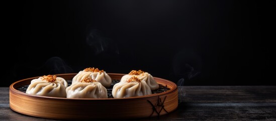 Sticker - Copy space image of Chinese meat dumpling Baozi a popular Asian food presented in a dim sum bamboo steamer and placed on a wooden board against a backdrop of black slate stone