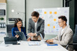 © laddawan - Office colleagues have a casual discussion. During a meeting in a conference room, a group of Asian business teem sit in the conference room