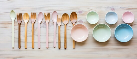 Aufkleber - A minimal and elegant flat lay view of a gray wooden background featuring a beautiful collection of empty pastel plastic tableware bowls spoons knives and forks Perfect for copy space images