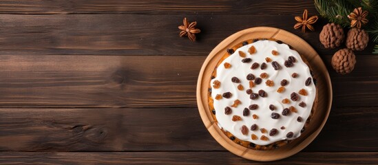 Sticker - A close up view from above of a white glaze Christmas cake with raisins placed on an old wooden cutting board on a table along with a whole apple Ample copy space image available