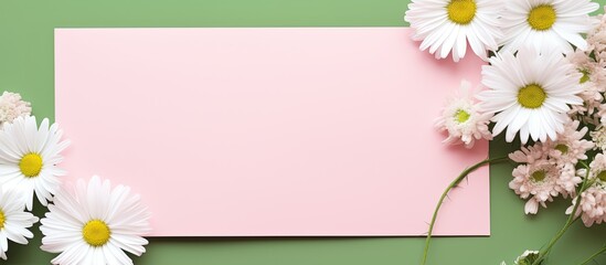 Sticker - A stylish mock up with a top view of a greeting or invitation card surrounded by daisy flowers and a green reed plant on a pink pastel background Ample copy space is available