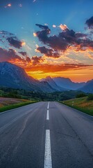 Canvas Print - Empty highway in the middle of flowering meadows, steep mountain peaks in the background, sky illuminated by sunset rays, incredible nature