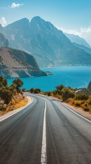Canvas Print - Empty highway on the background of steep mountain peaks, sea coast on one side of the road, blue water, clear sunny day, bright rays