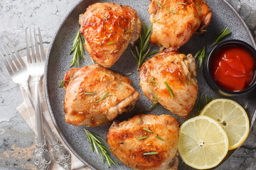 Wall Mural - Delicious homemade Lemon rosemary chicken thighs served with ketchup close-up in a plate on the table. Horizontal top view from above